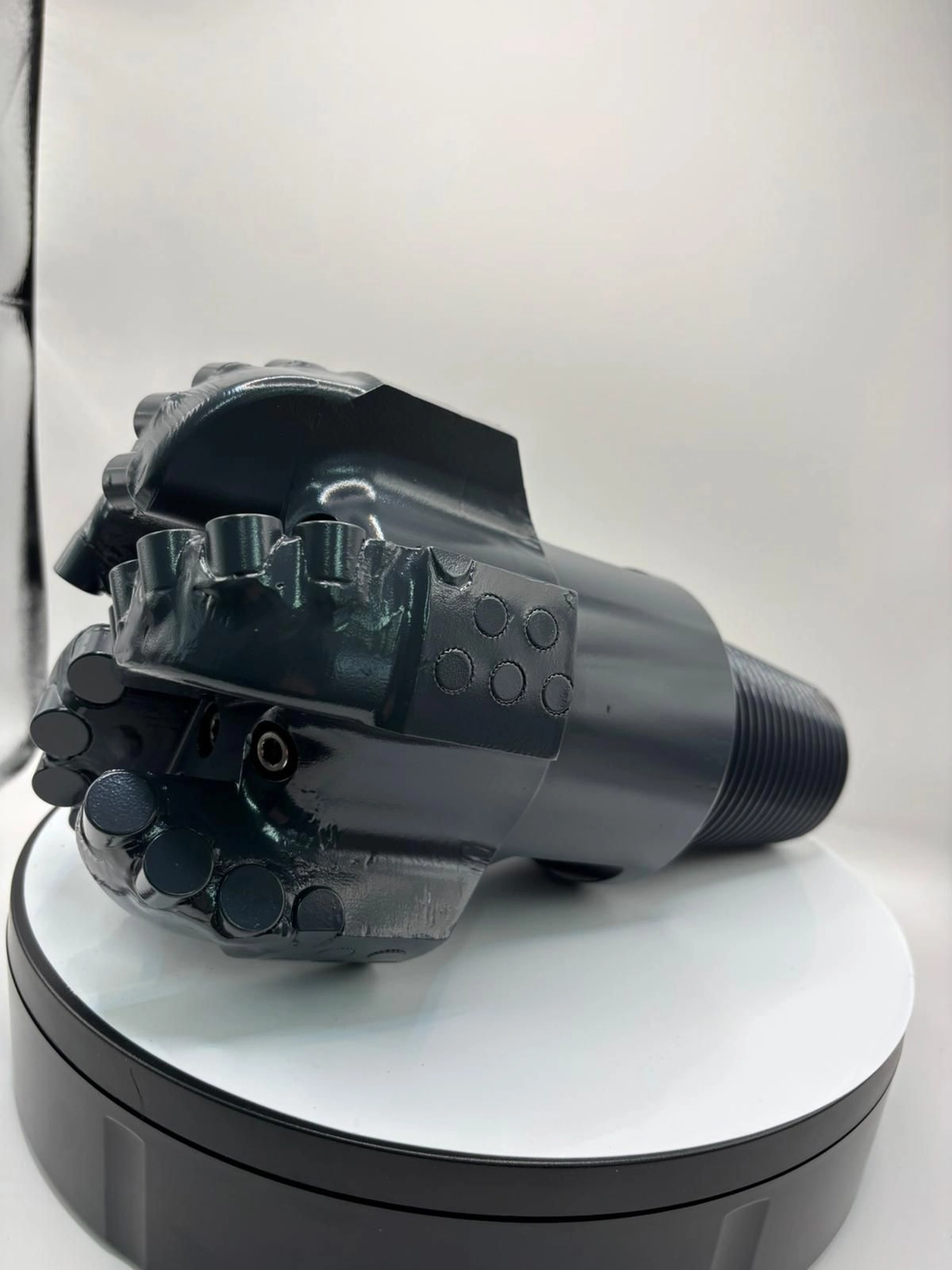 H-Tools - Hochleistungs-Gesteinsbohrkronen - Ein schwarzer PDC-Bohrer ruht auf einem weißen, drehbaren Präsentationsständer.