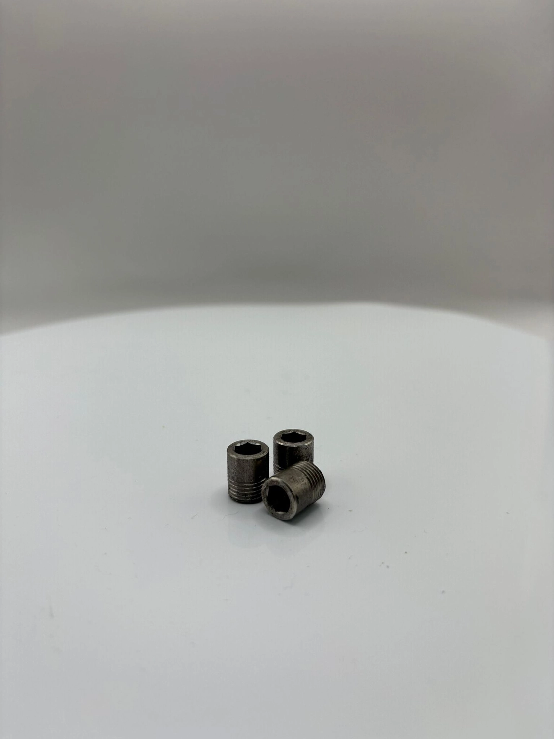 H-Tools - Hochleistungs-Gesteinsbohrkronen - Eine Gruppe von fünf schwarzen, zylindrischen Industrieschneidgeräten auf einer weißen, kreisförmigen Drehplattform, von denen einige leicht abgewinkelt oder abgestuft erscheinen.