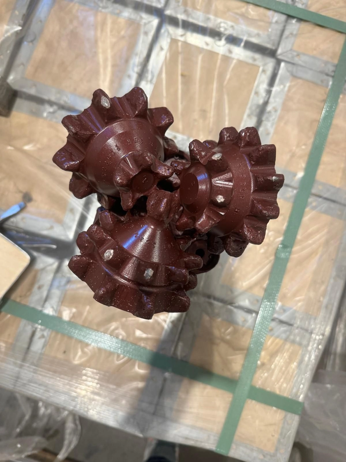 H-Tools - Hochleistungs-Gesteinsbohrkronen - Ein großer, rötlich-violetter Kegelbohrer mit zwei sichtbaren Kegeln, der in einer Holzkiste liegt.