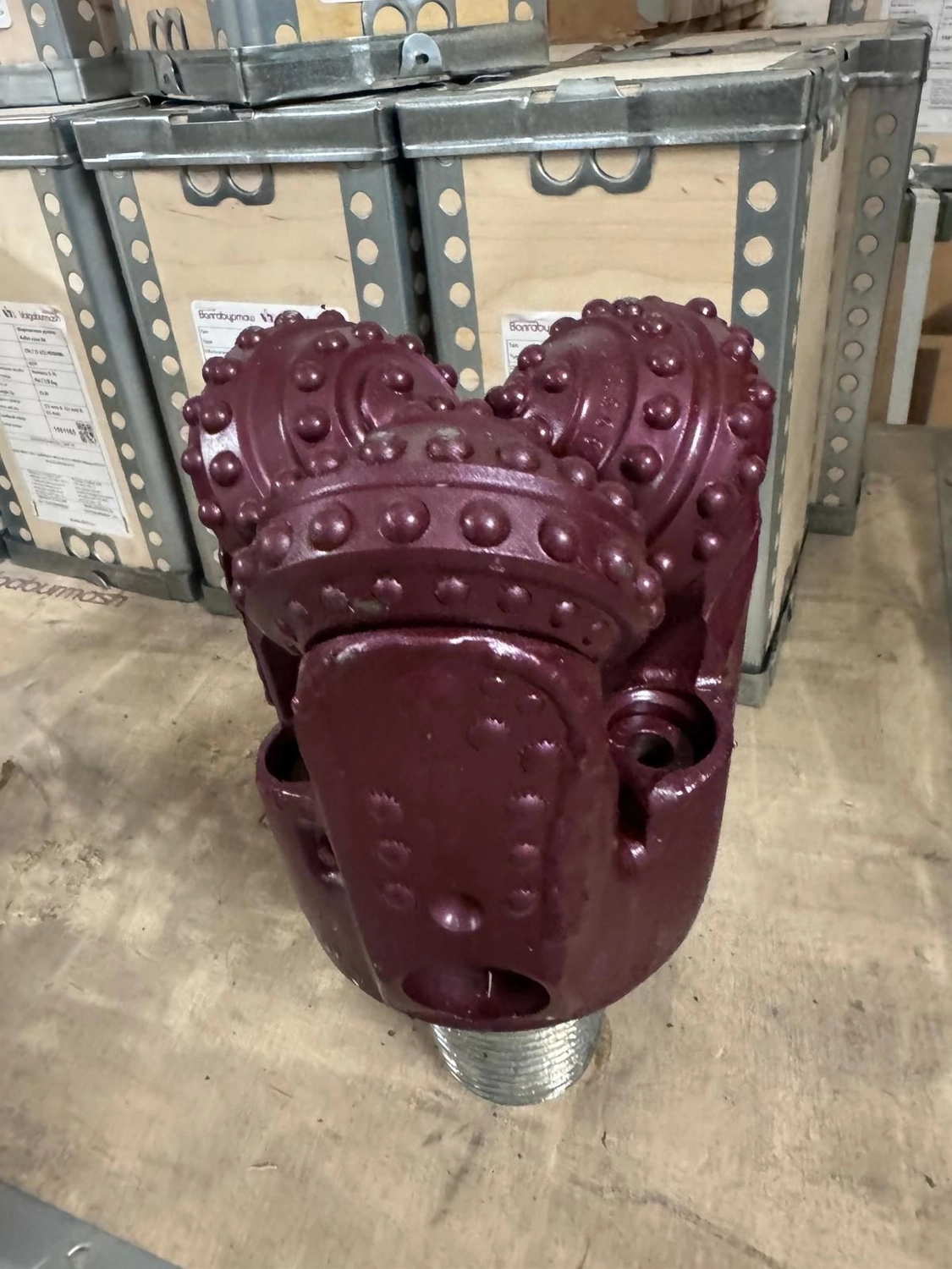 H-Tools - Hochleistungs-Gesteinsbohrkronen - Ein großer, rötlich-violetter Kegelbohrer mit zwei sichtbaren Kegeln, der in einer Holzkiste liegt.