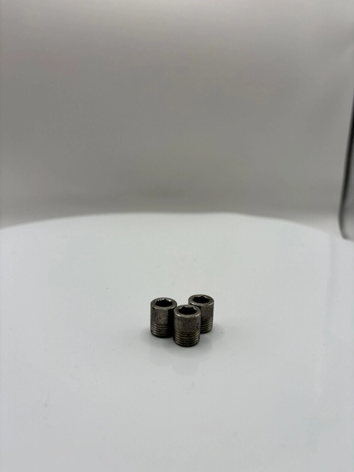 H-Tools - Hochleistungs-Gesteinsbohrkronen - Nahaufnahme mehrerer kleiner, metallener, konischer Bohrer oder Einsätze auf einem weißen, drehbaren Präsentationsständer.