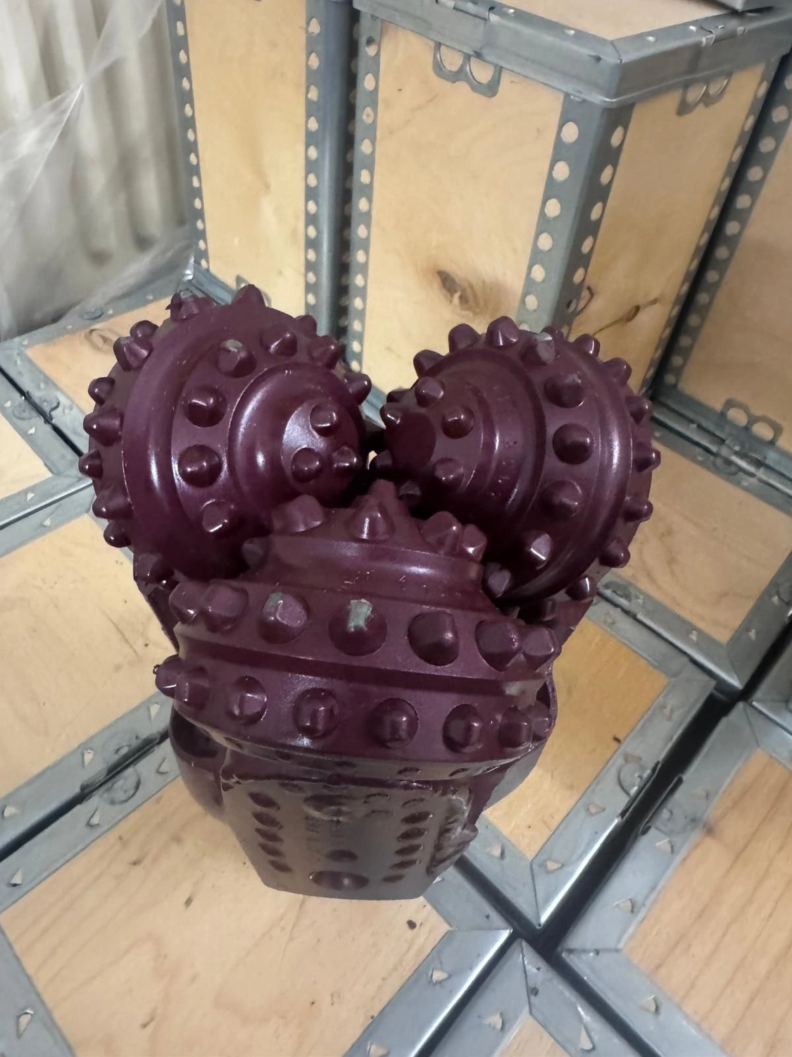 H-Tools - Hochleistungs-Gesteinsbohrkronen - Ein großer, rötlich-violetter Kegelbohrer mit zwei sichtbaren Kegeln, der in einer Holzkiste liegt.